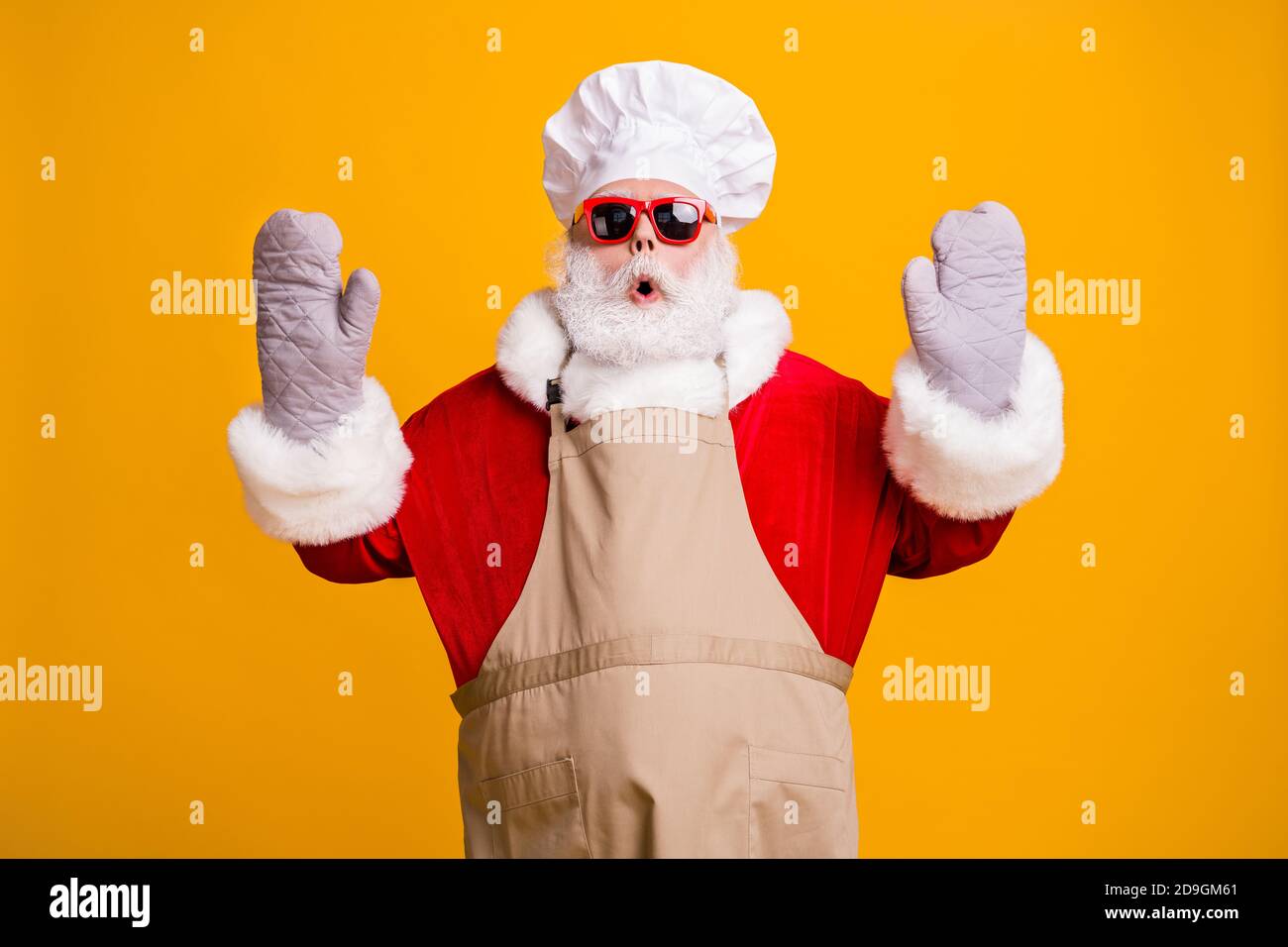 Photo of confused santa grandpa chef headwear bake cookery raise hands gloves open mouth tried help did wrong move wear red costume coat sun specs cap Stock Photo
