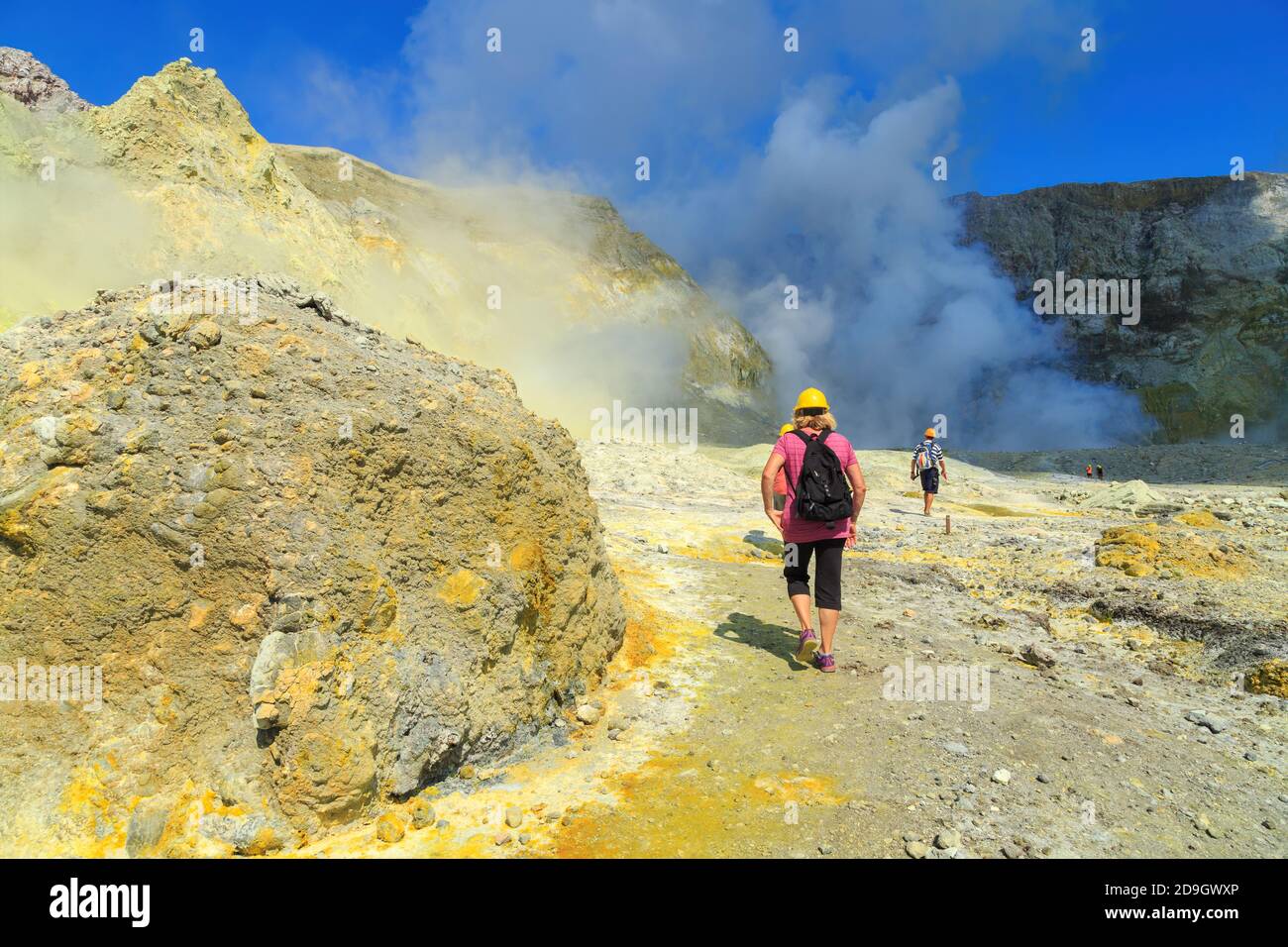 Tourists walking through the landscape of White Island, an active volcano in the Bay of Plenty, New Zealand, towards the steaming crater lake Stock Photo