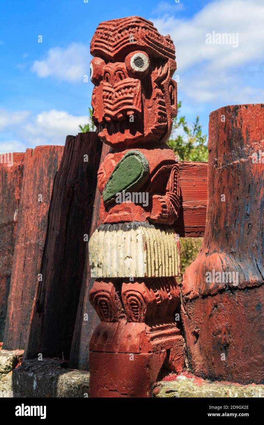 An old New Zealand Maori wood carving of a warrior holding a mere (a greenstone club), set into a fence Stock Photo