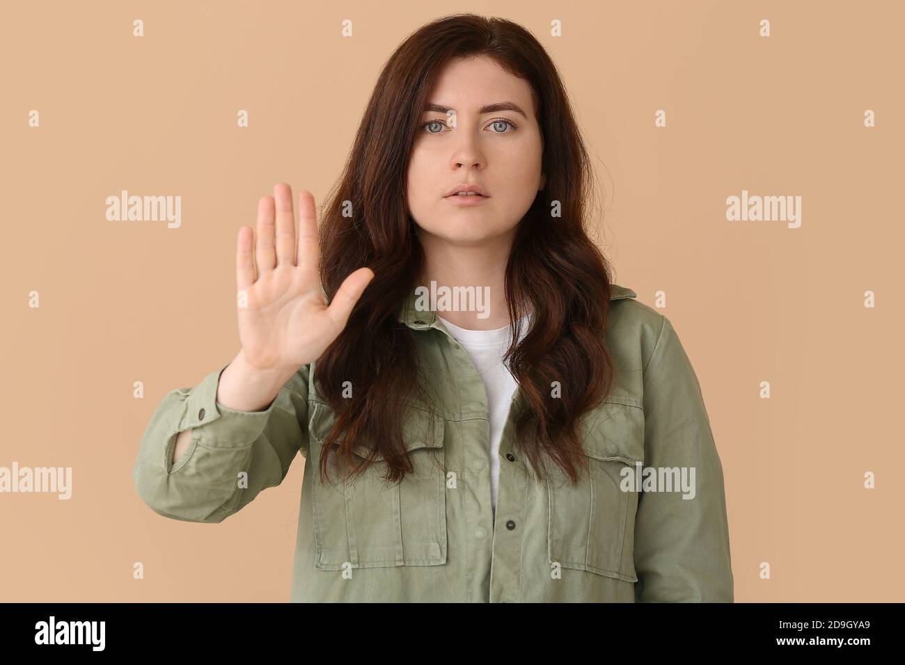 Young deaf mute woman using sign language on color background Stock Photo