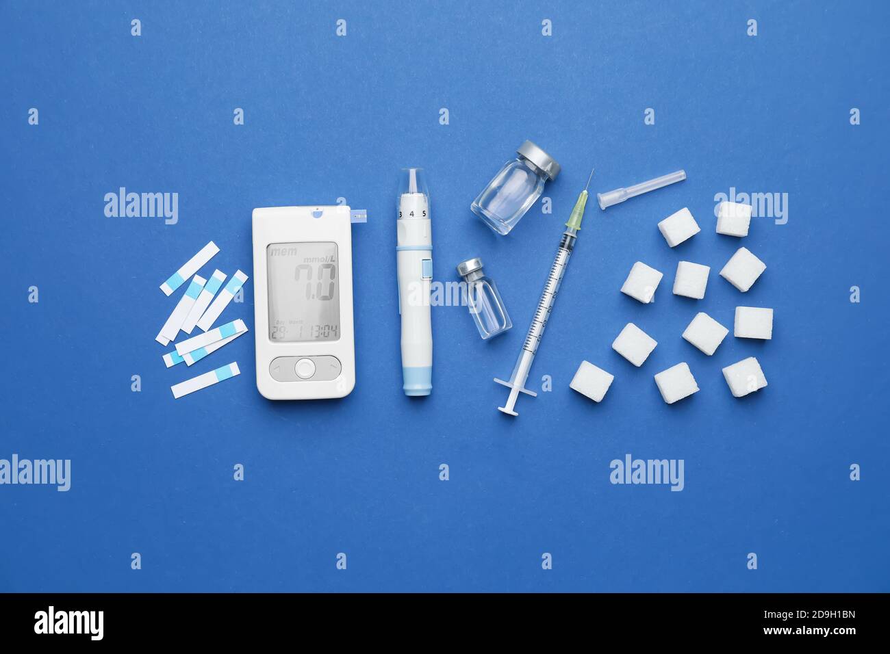 Glucometer with sugar cubes, bottles of insulin, test strips, lancet pen and syringe on color background. Diabetes concept Stock Photo