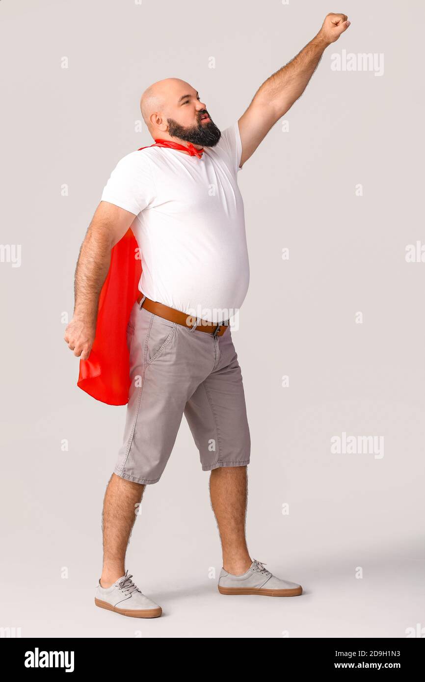 Overweight man in cape on grey background. Weight loss concept Stock Photo