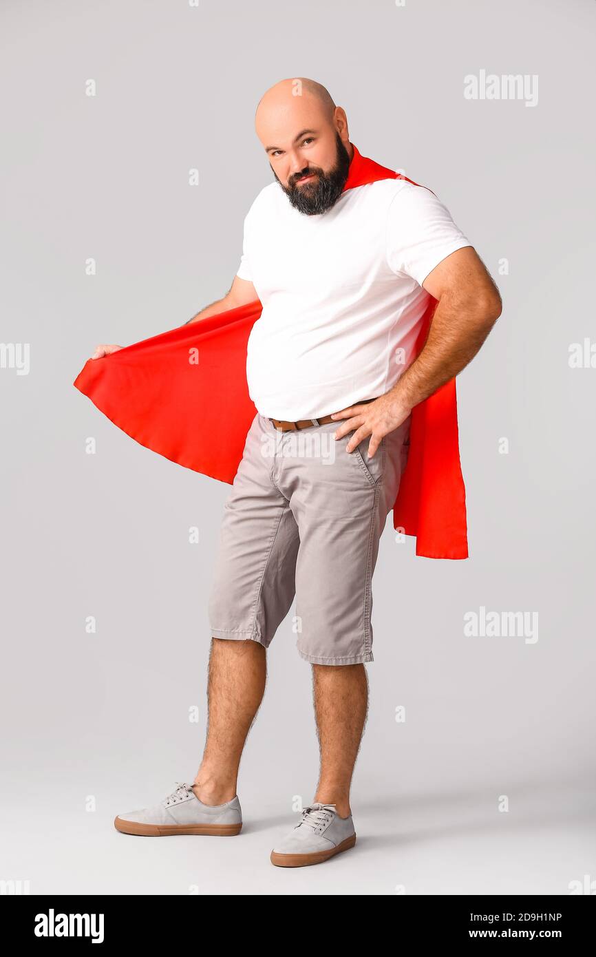 Overweight man in cape on grey background. Weight loss concept Stock Photo
