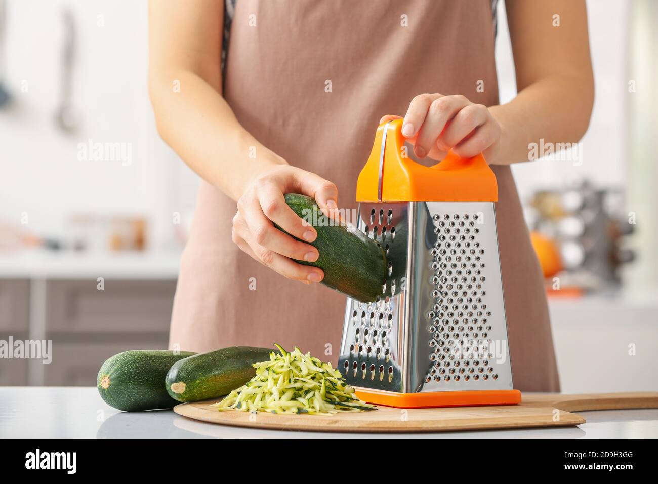 Woman grating zucchini in kitchen Stock Photo Alamy
