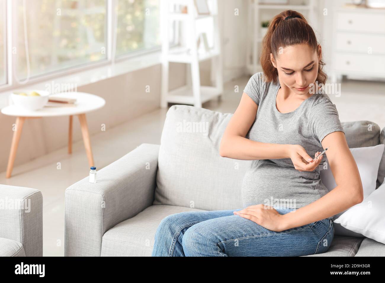 Pregnant diabetic woman giving herself insulin injection at home Stock