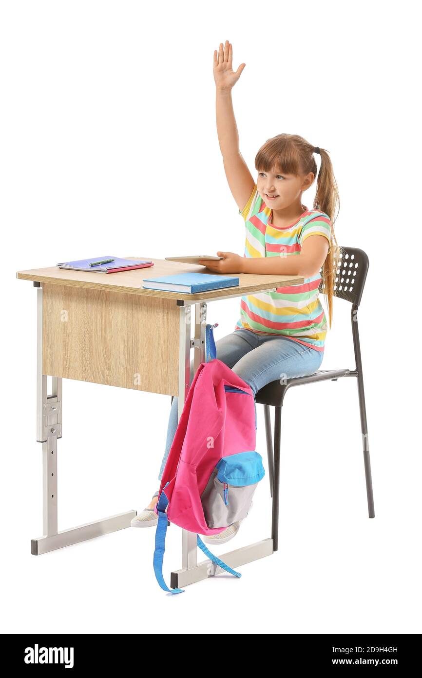 Little pupil with raised hand sitting at school desk against white background Stock Photo