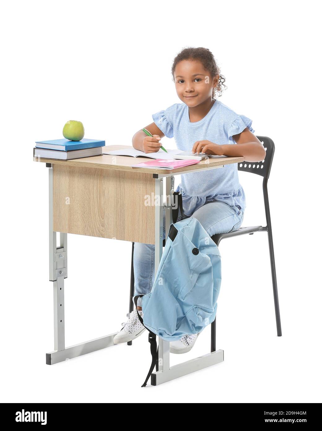 Little African-American pupil sitting at school desk against white background Stock Photo