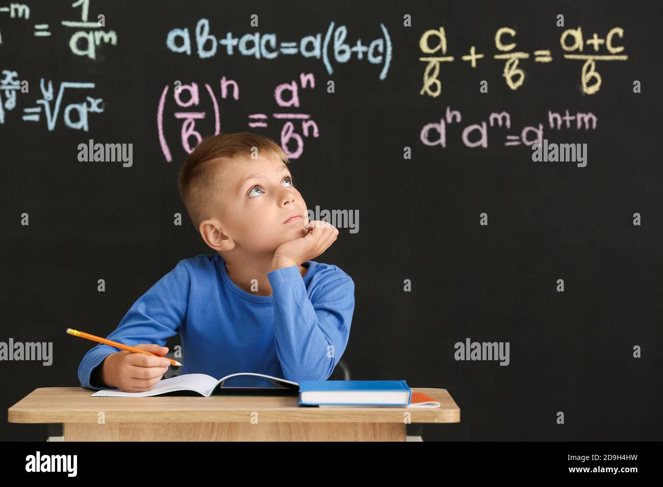 Cute pupil sitting at desk during lesson in classroom Stock Photo - Alamy