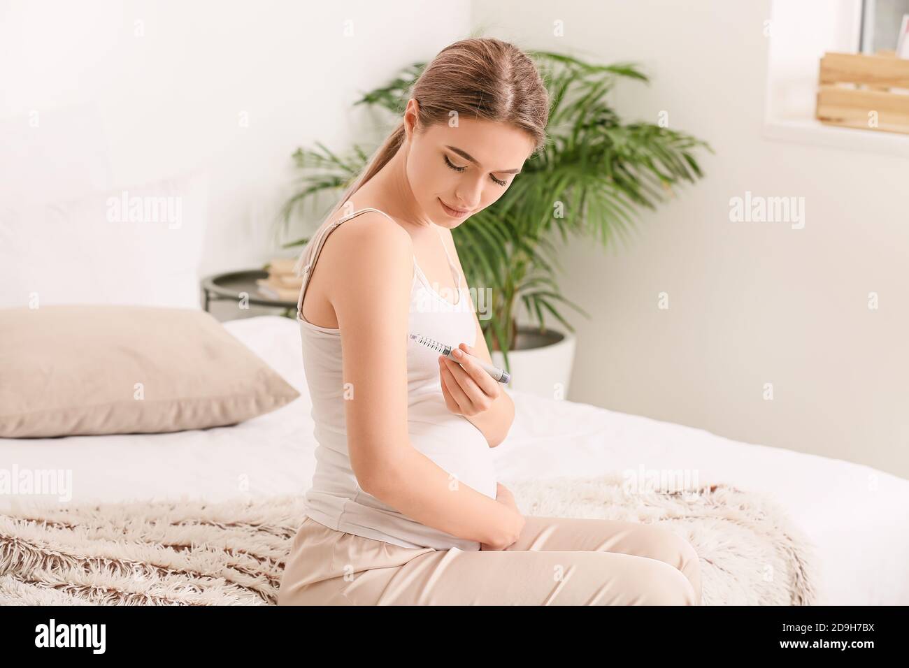 Pregnant diabetic woman giving herself insulin injection at home Stock