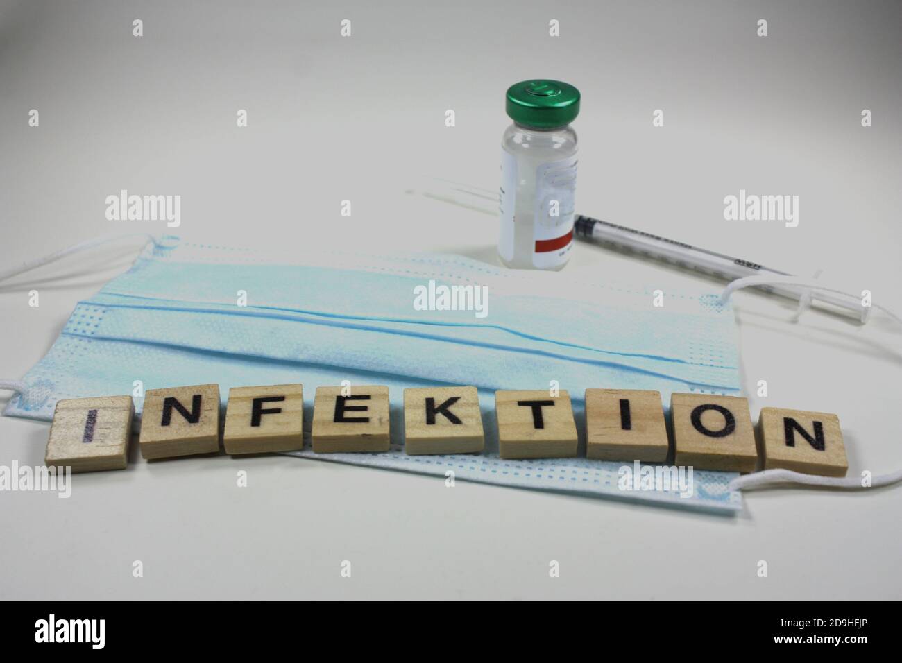 Word 'infektion' made of wooden blocks on a protective face mask Stock Photo