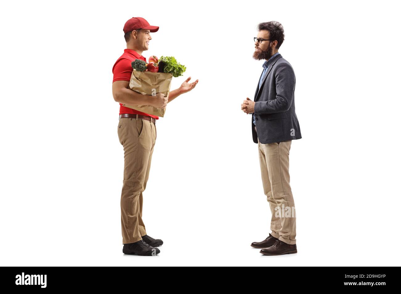 Full length profile shot of a delivery courier with a grocery bag talking to a bearded male customer isolated on white background Stock Photo