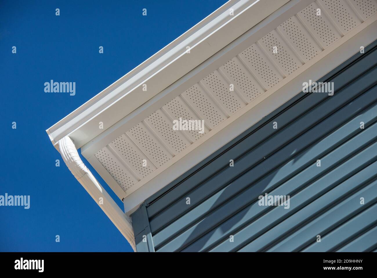 Colonial white gutter guard system, fascia, drip edge, soffit providing ventilation to the attic, with pacific blue shingle siding luxury house Stock Photo