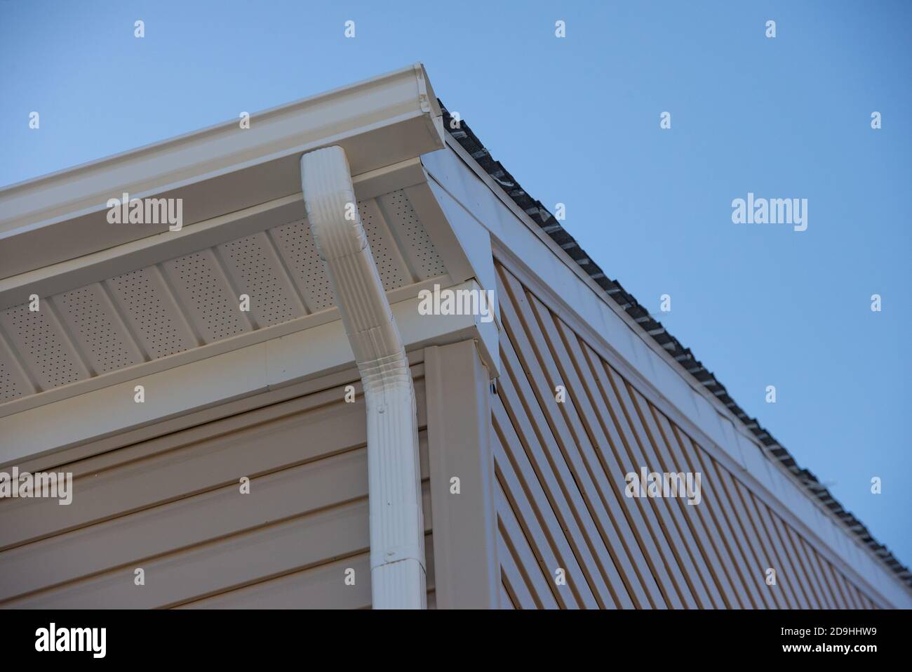 Colonial white gutter guard system, fascia, drip edge, soffit providing ventilation to the attic, with beige vinyl horizontal siding luxury Stock Photo