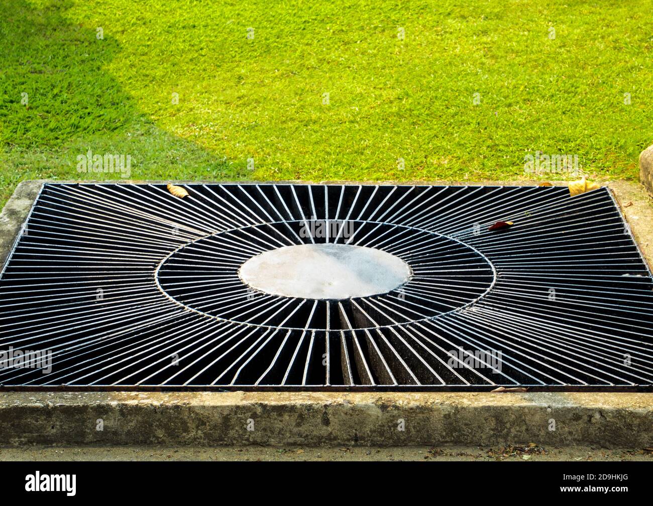 Grate the drain pipe beside the lawn in the park Stock Photo