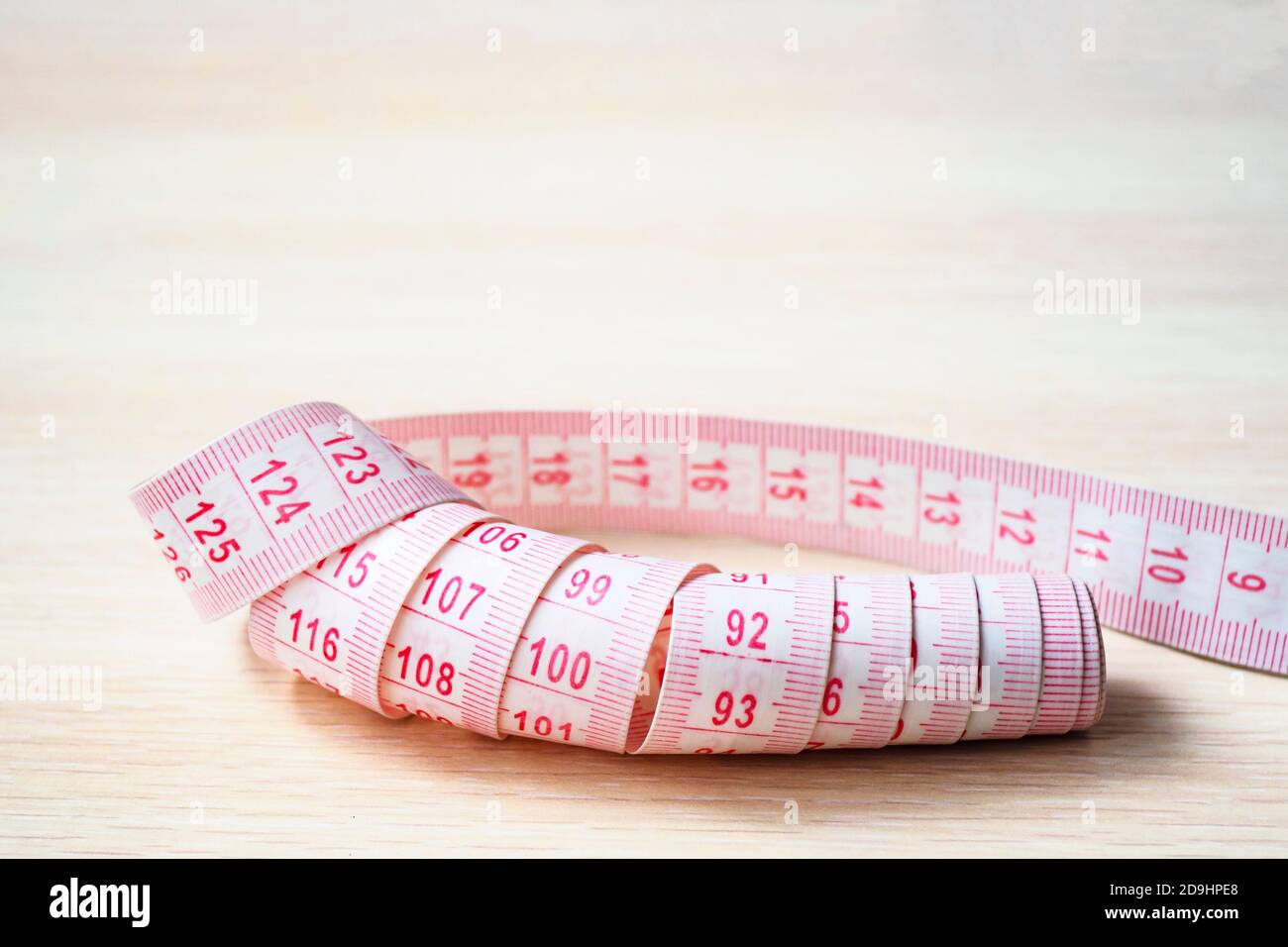 close up of measuring tape on a beige wooden background, selective focus, copy space Stock Photo