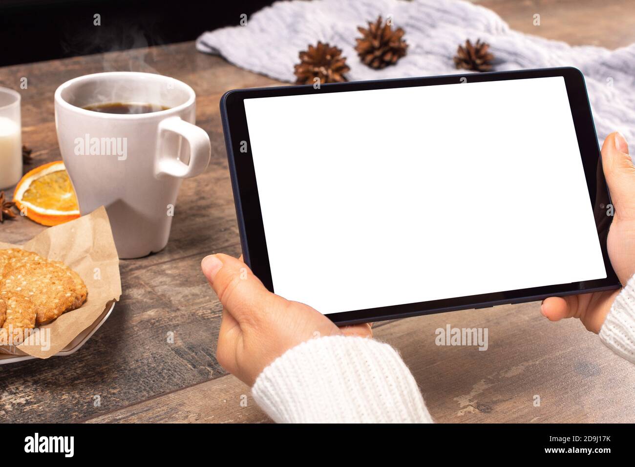 Mockup tablet pc. woman's hands holding black tablet pc with blank white screen horizontally while sitting in cafe. winter Christmas time Stock Photo