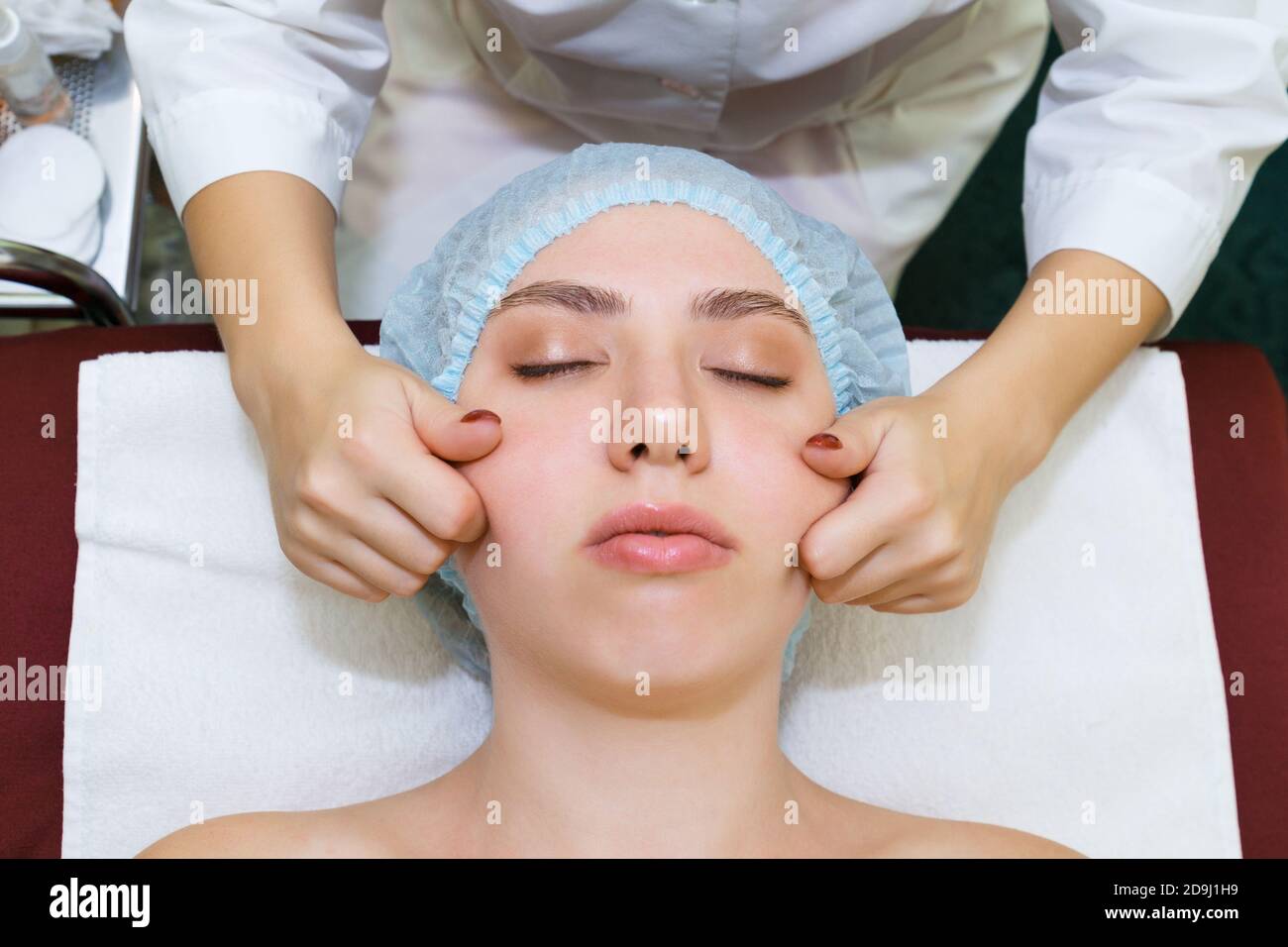 The masseur cosmetologist conducts a procedure for rejuvenating the skin of the face using manual massage. top view close up Stock Photo