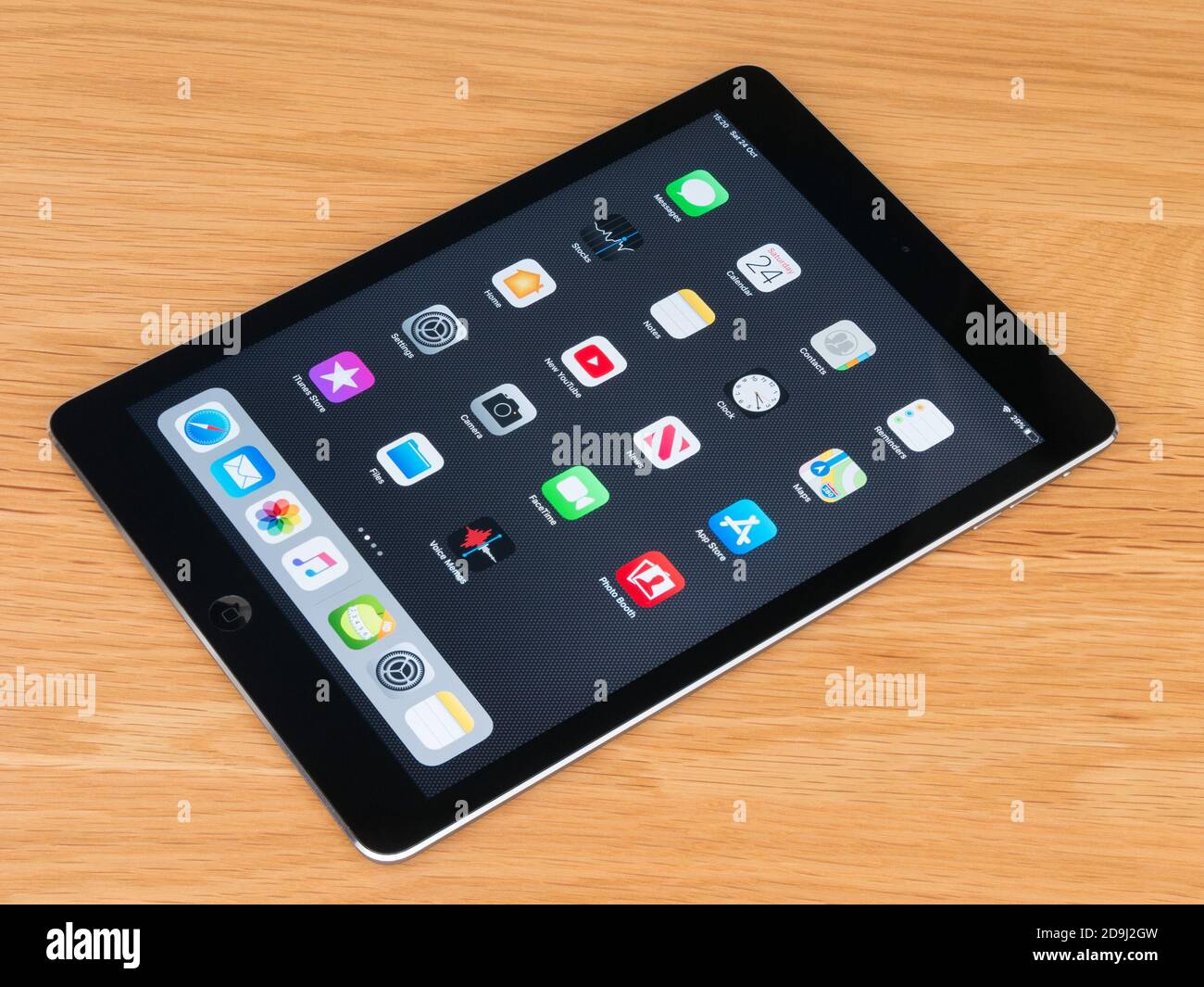 Black iPad Air 1 Tablet Computer showing icons on home screen on wooden desk Stock Photo