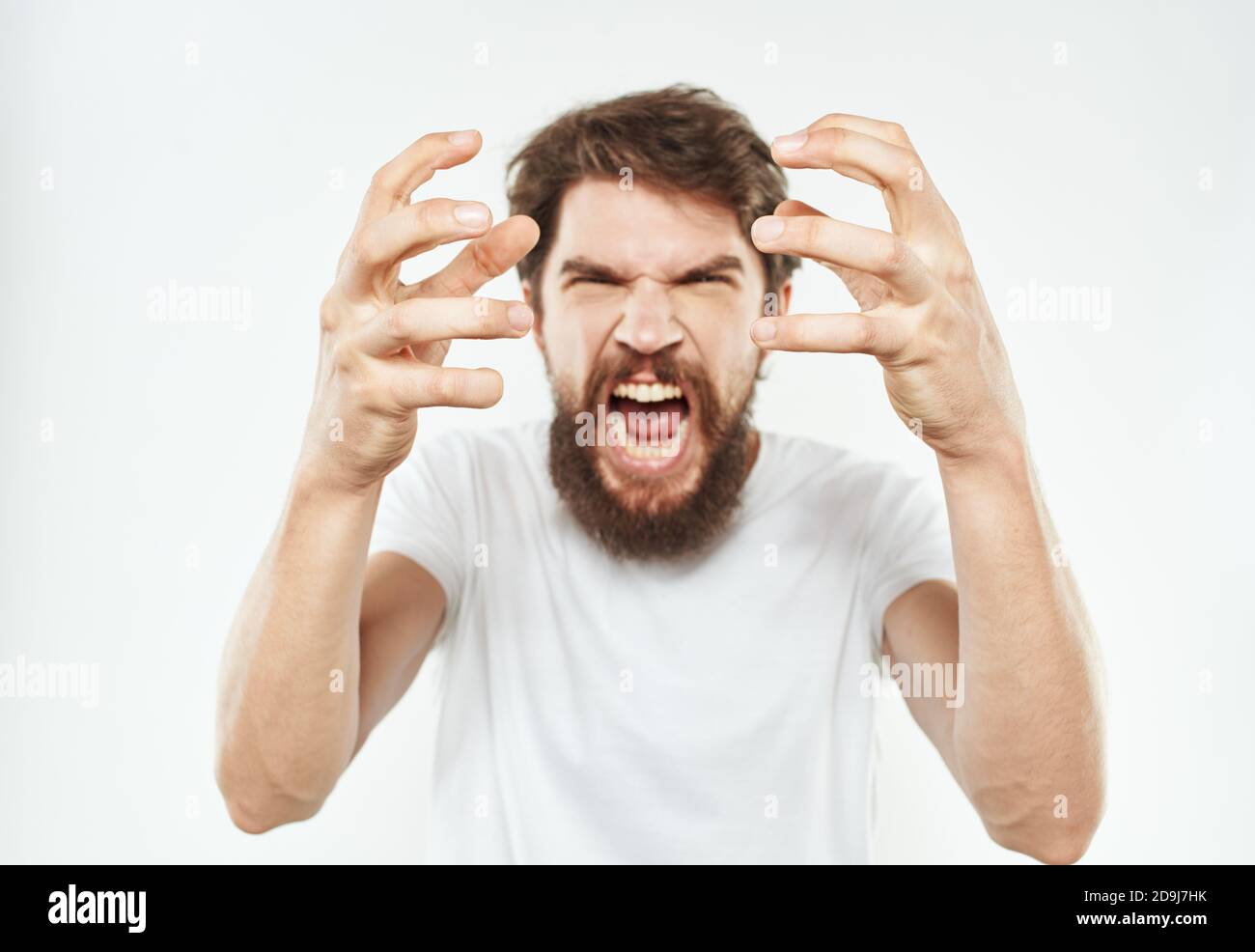 Aggressive man gestures with his hands on a light background and a ...