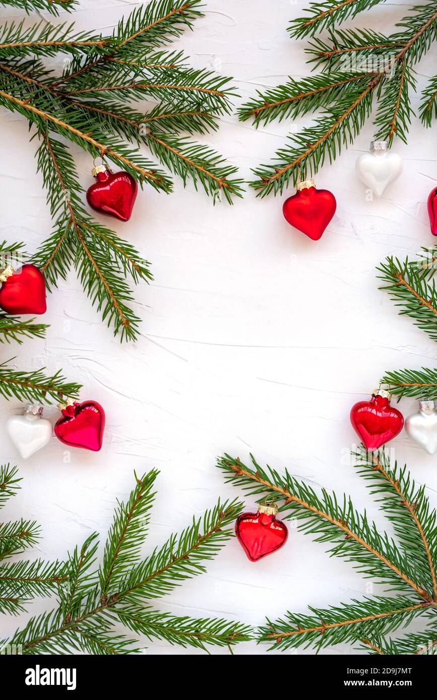 Frame made of branches of a Christmas tree and glass decorations in the shape of hearts. Stock Photo