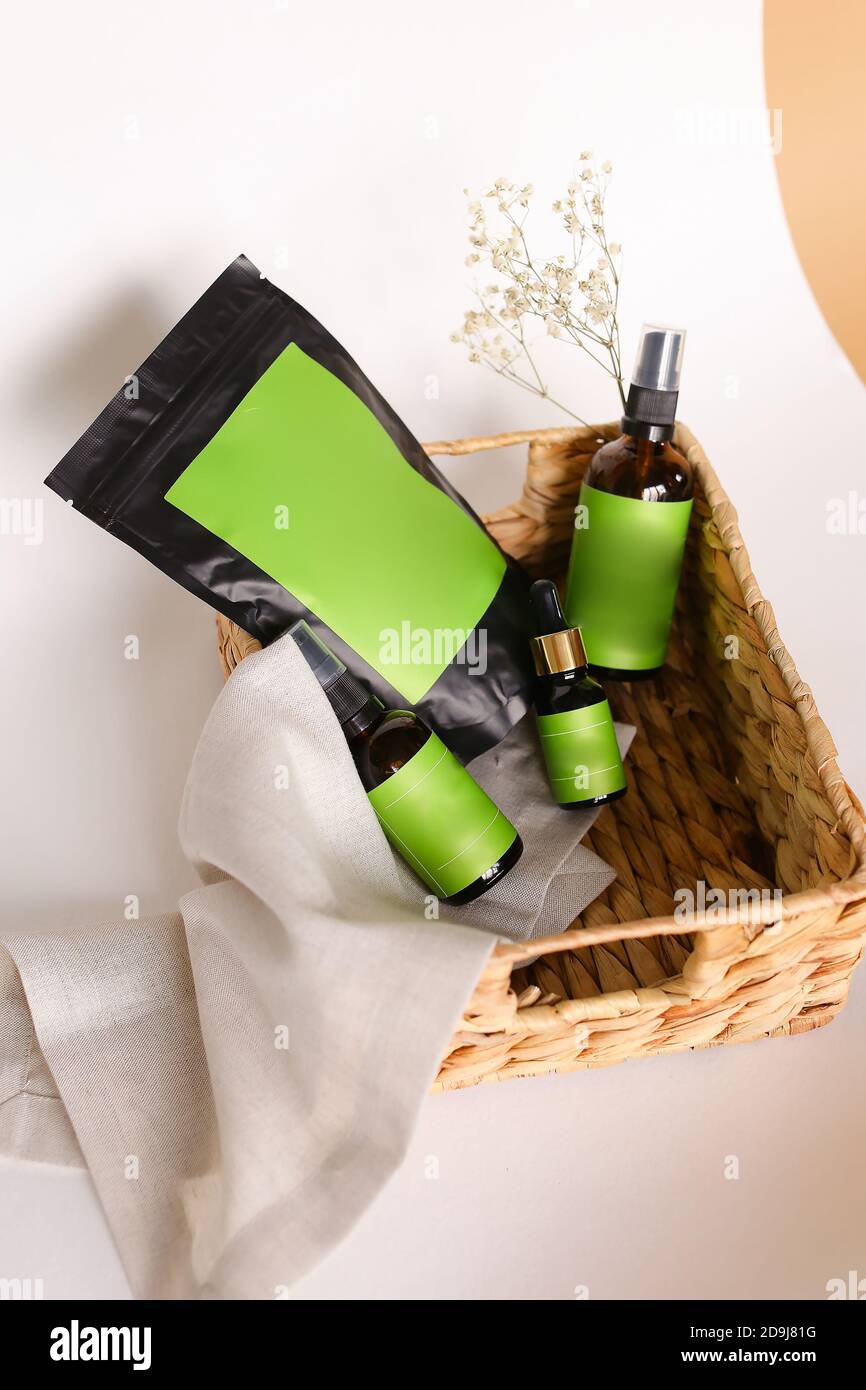 Doy pack and spray bottles with cosmetic products in wicker basket, green space for your brand. Stock Photo