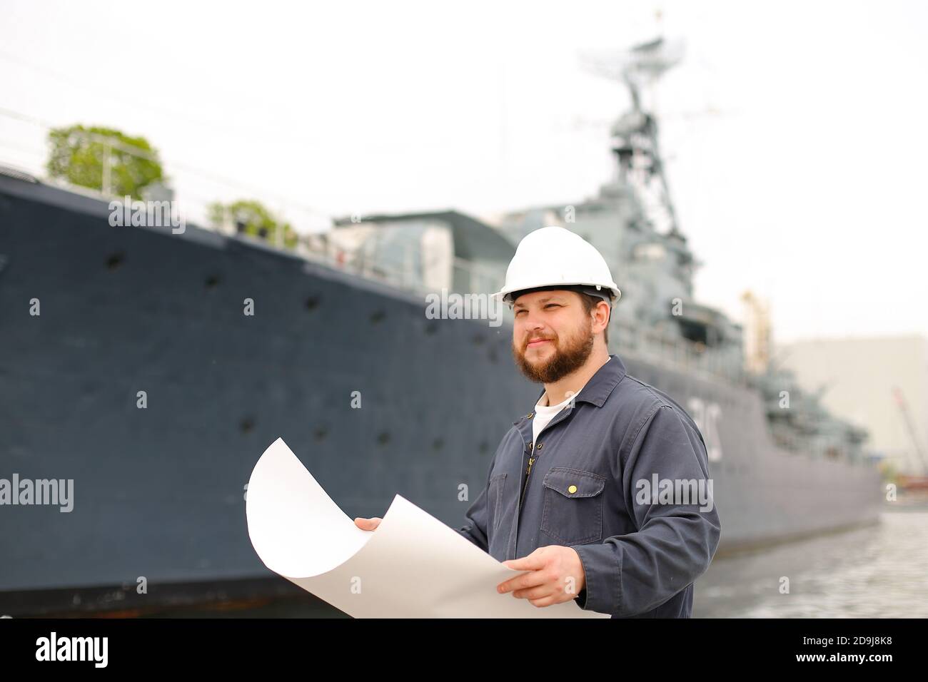 Maritime captain reading documents and standing near vessel. Stock Photo