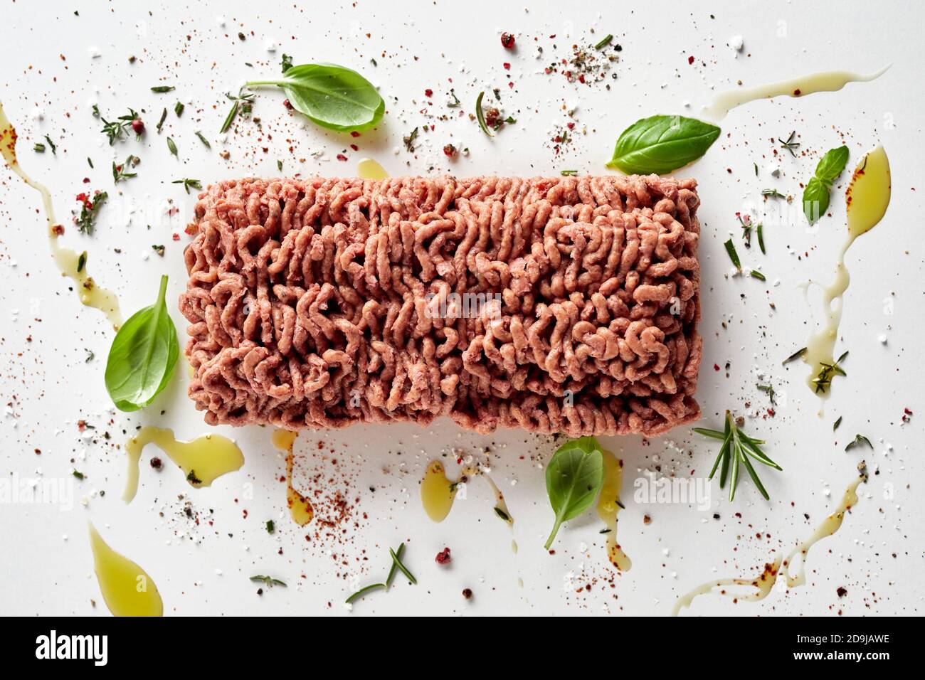 Block of raw vegan mince meat surrounded with scattered with herbs and ...