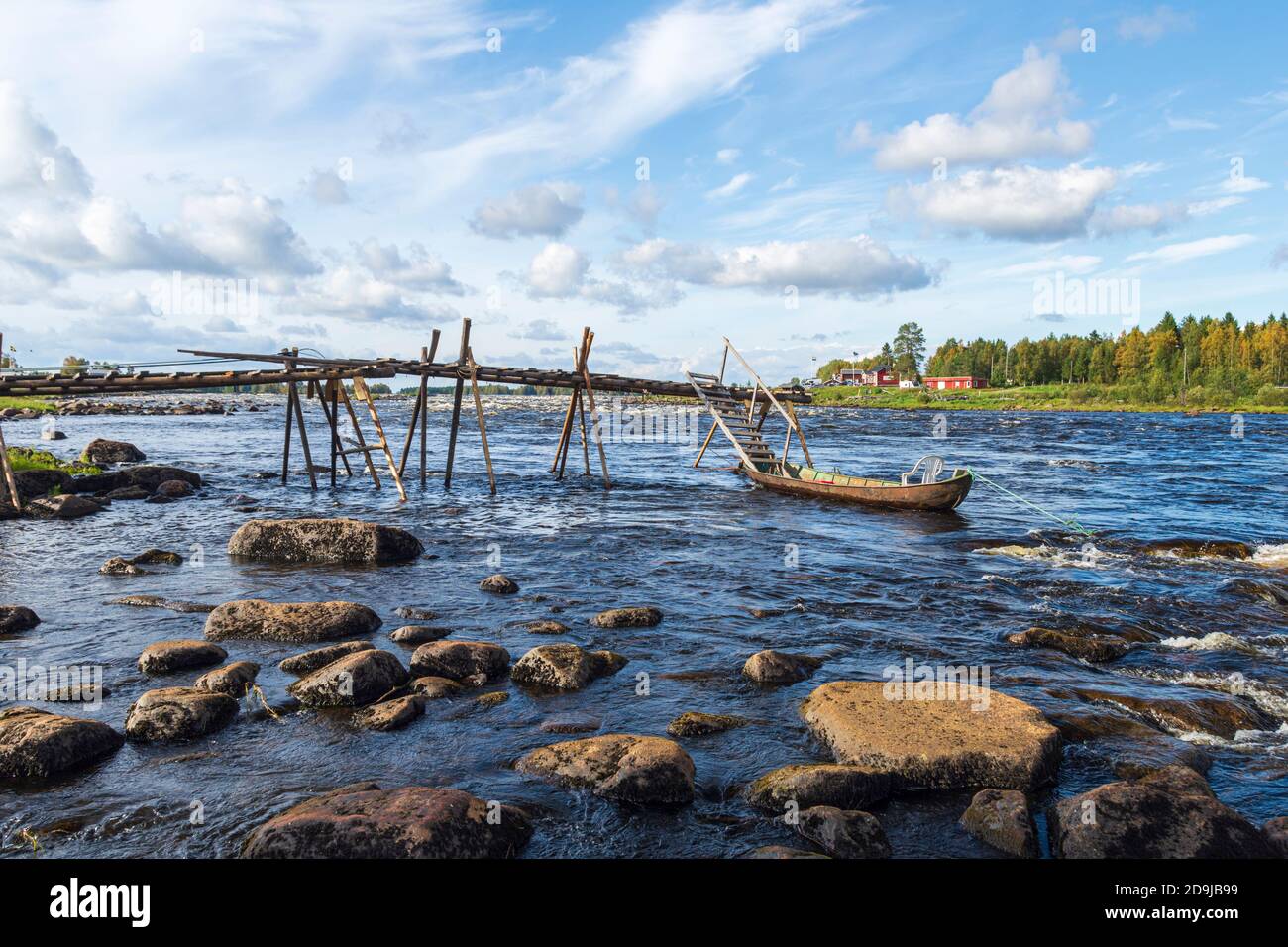 Bridge used for fishing with handle landing net out to the rapid with a boat attached and with a blue sky in background, picture from kukkola rapid in Stock Photo