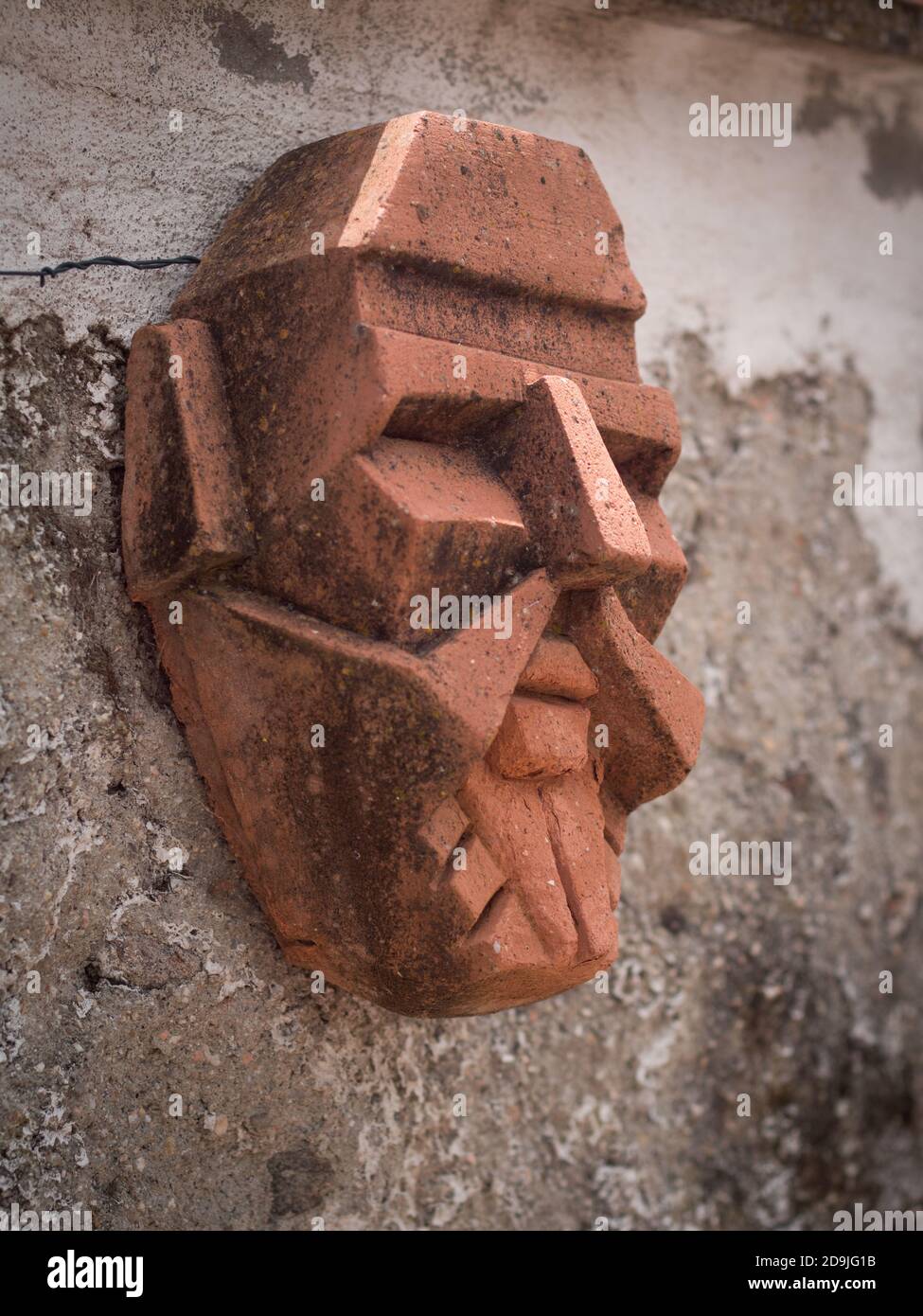 Side view of terracota male mask hanged on a walk. Stock Photo