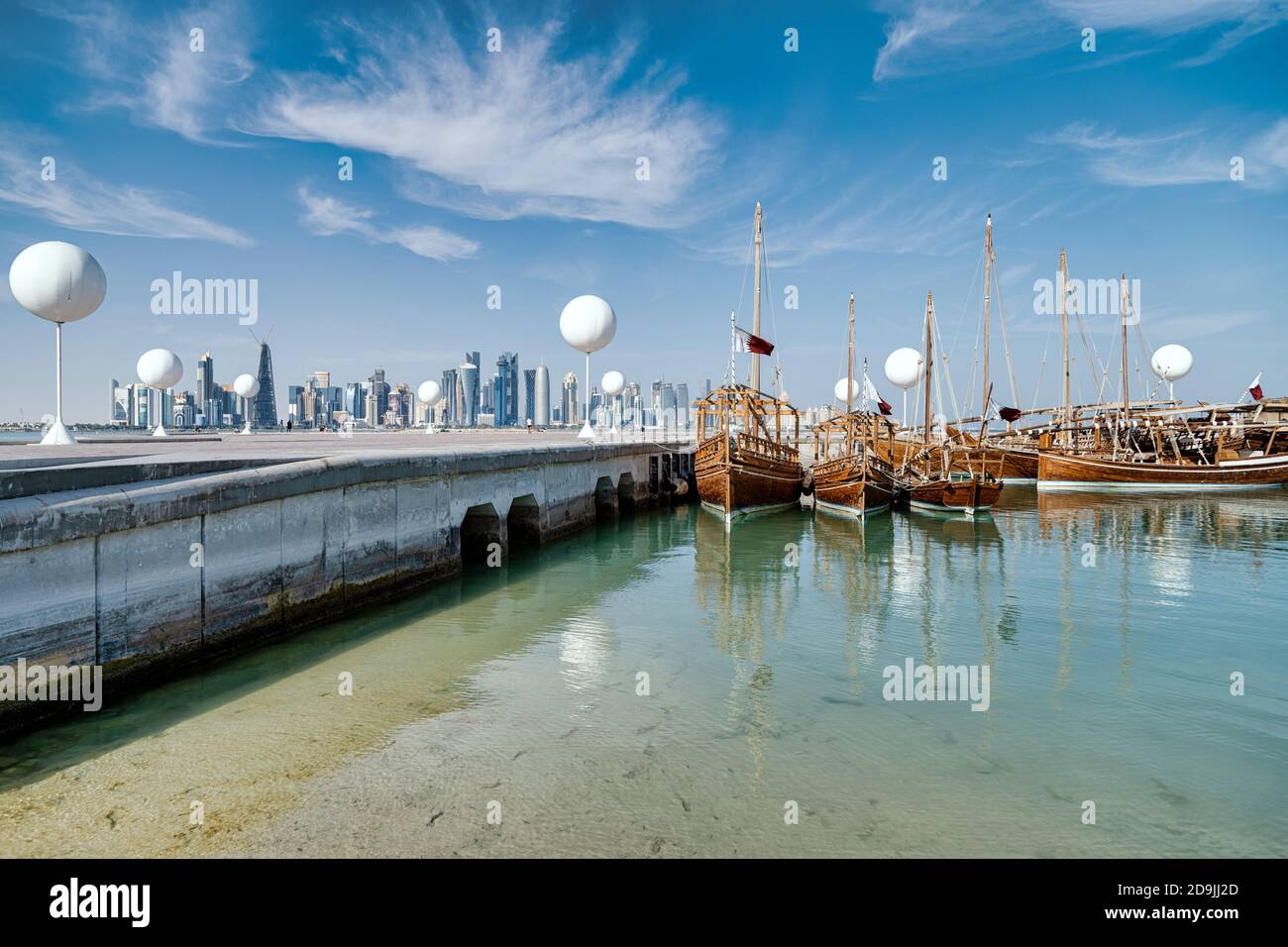 DOHA, QATAR - 1. JANUARY 2020: Traditional Qatari Dhow boats in the harbor with iconic Doha skyline in the background, Doha, Qatar, Middle East. Stock Photo