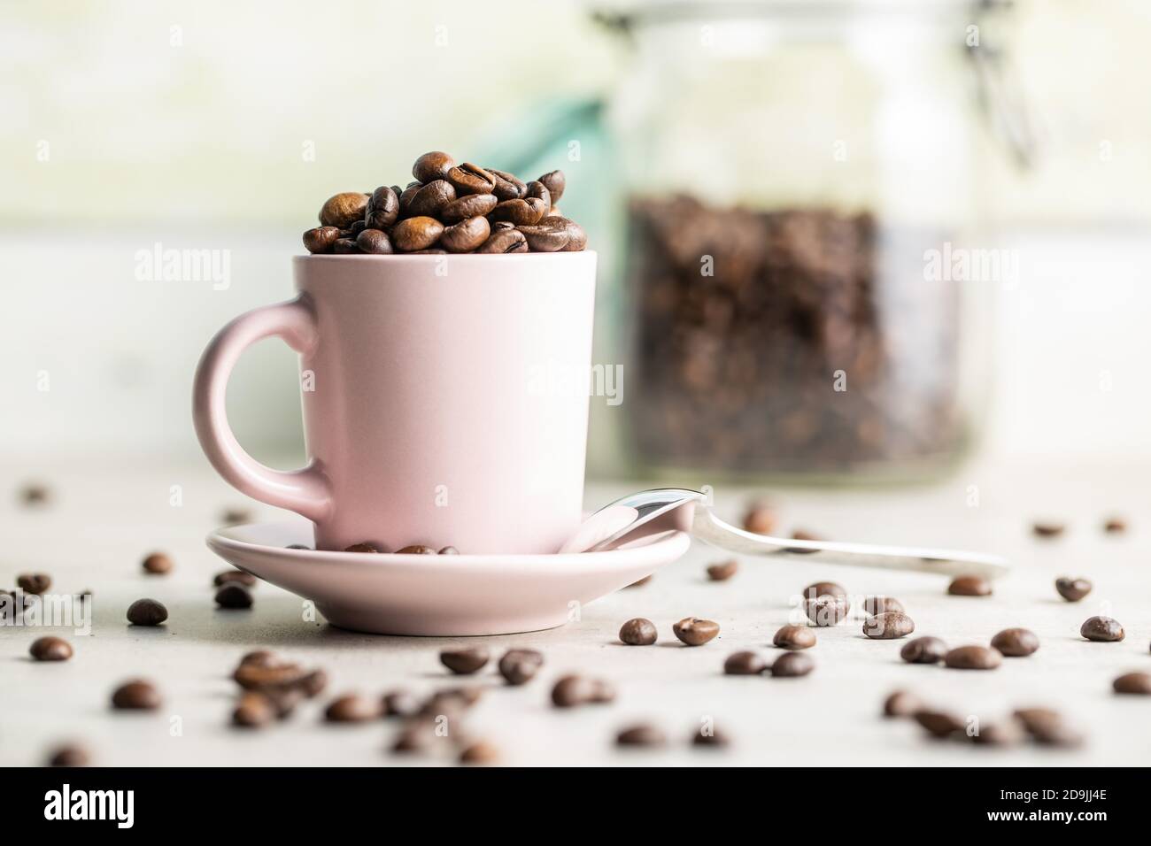Roasted coffee beans in cup on white table. Stock Photo