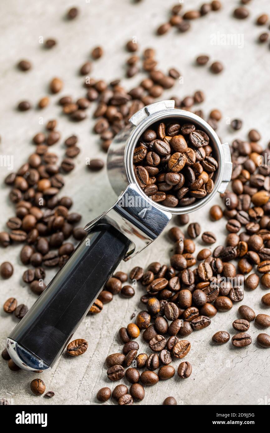 Roasted coffee beans in coffee filter holder on white table. Stock Photo