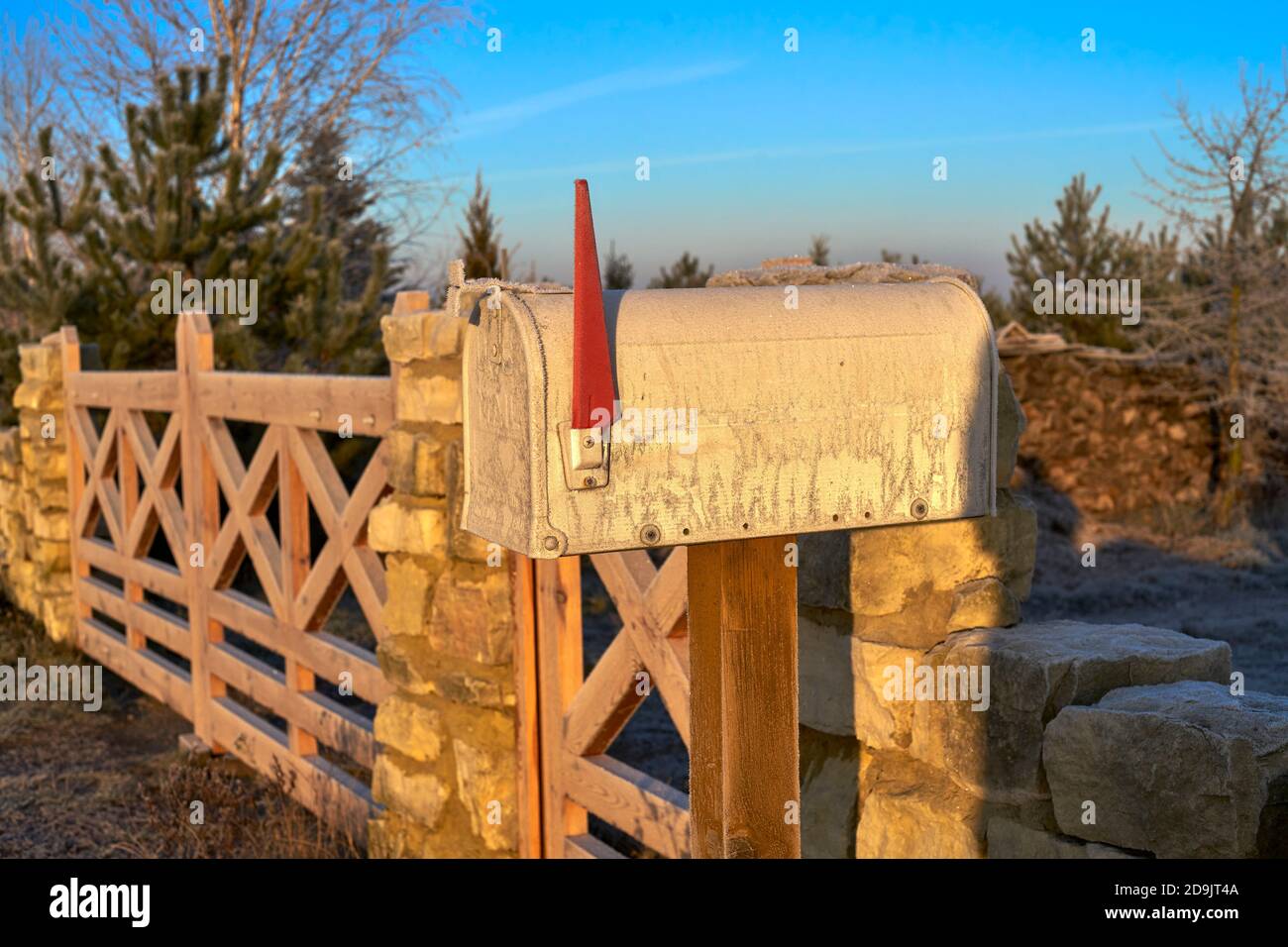 mailbox at the village wooden gate and stone fence on a winter morning Stock Photo