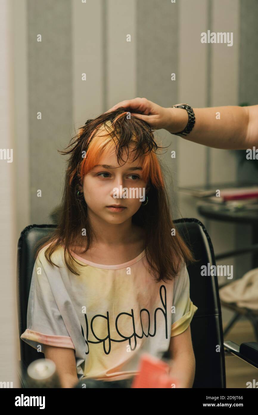Hairdresser making a hair style to cute little girl. A teenage girl has her  bangs lightened in a beauty salon. Orange bangs. The trend of bright hair  Stock Photo - Alamy