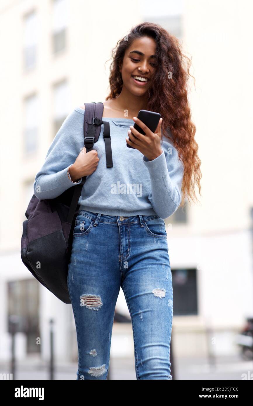 Portrait young woman walking with mobile phone and bag in city Stock Photo