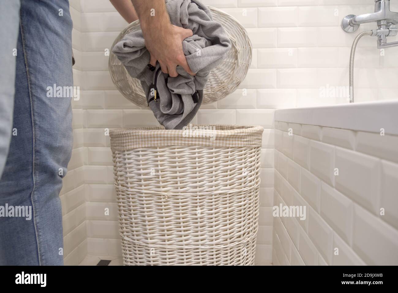 Man puts used dirty clothes in a dirty laundry basket. Stock Photo