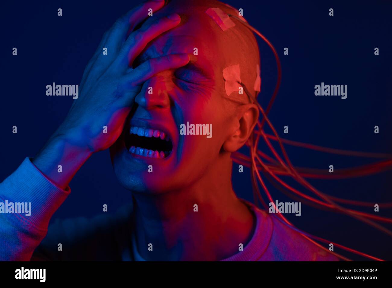 Man with electrodes in his head screams in horror, a polygraph lie detector test, memory Erasure. Stock Photo