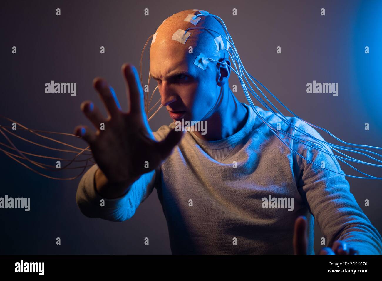 Man with a bald head with wires connected. Fear and anxiety. Examination of the brain, mind control. Stock Photo