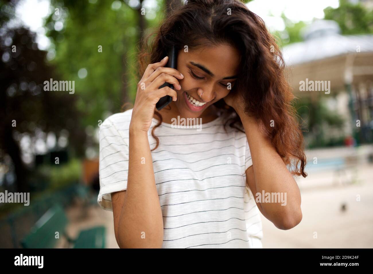 Close up portrait happy young indian woman talking with phone in park ...