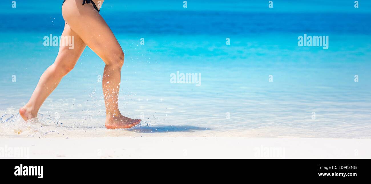 Detail of woman legs running on beach. Close-up of woman legs running on beach. Woman legs running, enjoying splashing beach aqua water, white sand Stock Photo