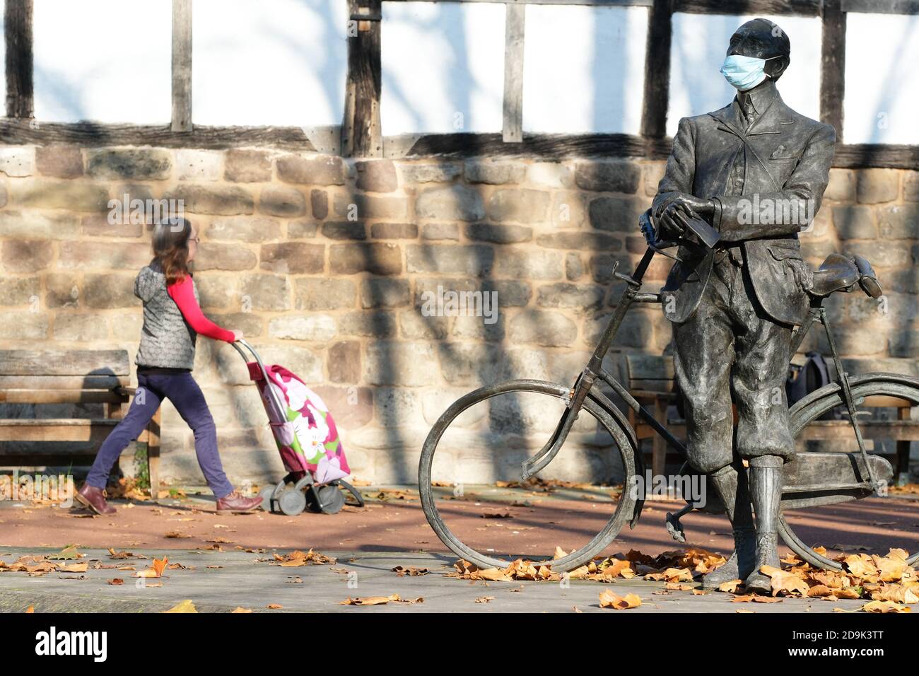 Hereford Herefordshire, Friday 6th November 2020 - UK Weather - Residents and statues enjoy the bright autumn sunny weather today. Golden autumn leaves surround a statue of composer Sir Edward Elgar complete with Covid facemask as local temperatures reach 10c. Forecast outlook is milder but with some rain this weekend. Photo Steven May / Alamy Live News Stock Photo