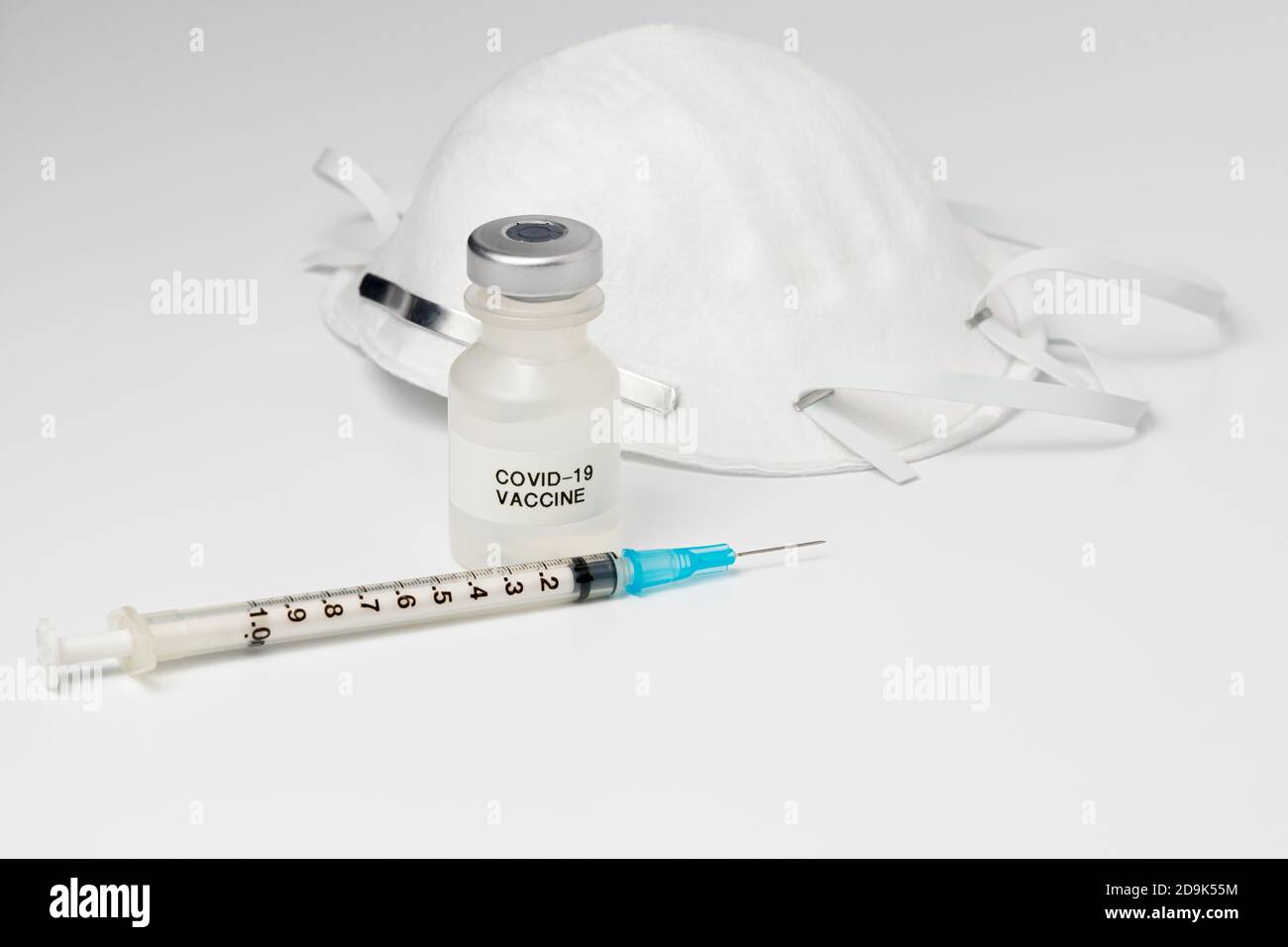 vial with Covid-19 vaccine, syringe and needle, and N95 face mask isolated on white background. Concept of coronavirus pandemic, immunization Stock Photo