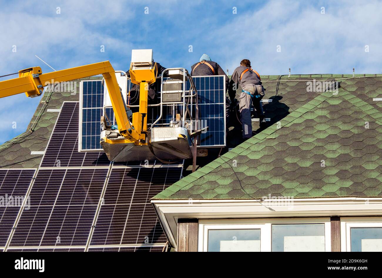 Workers installing solar panels on private home hexagonal roof felt on