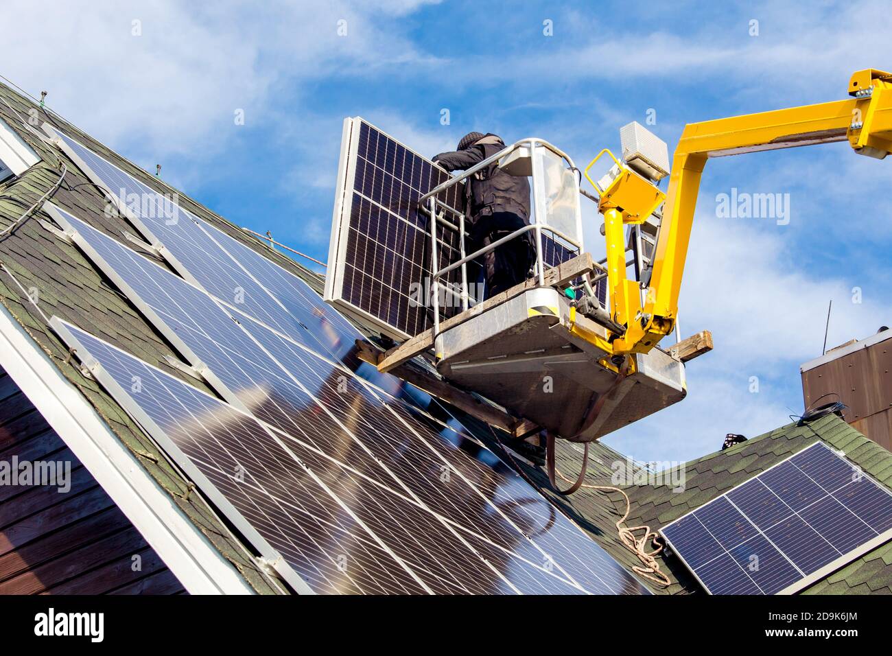 Workers installing solar panels on private home hexagonal roof felt on
