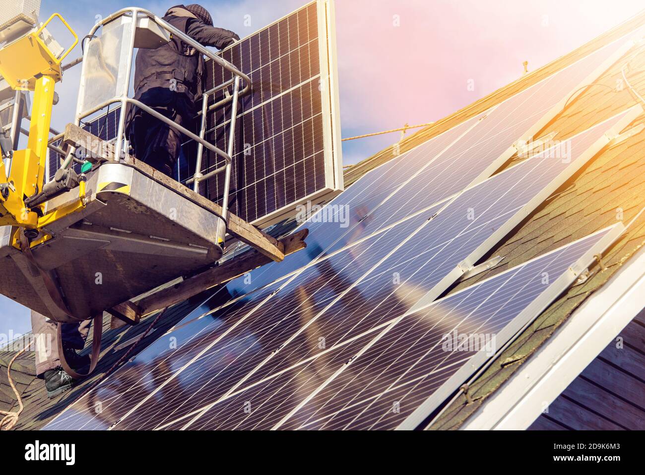 Workers installing solar panels on private home hexagonal roof felt on
