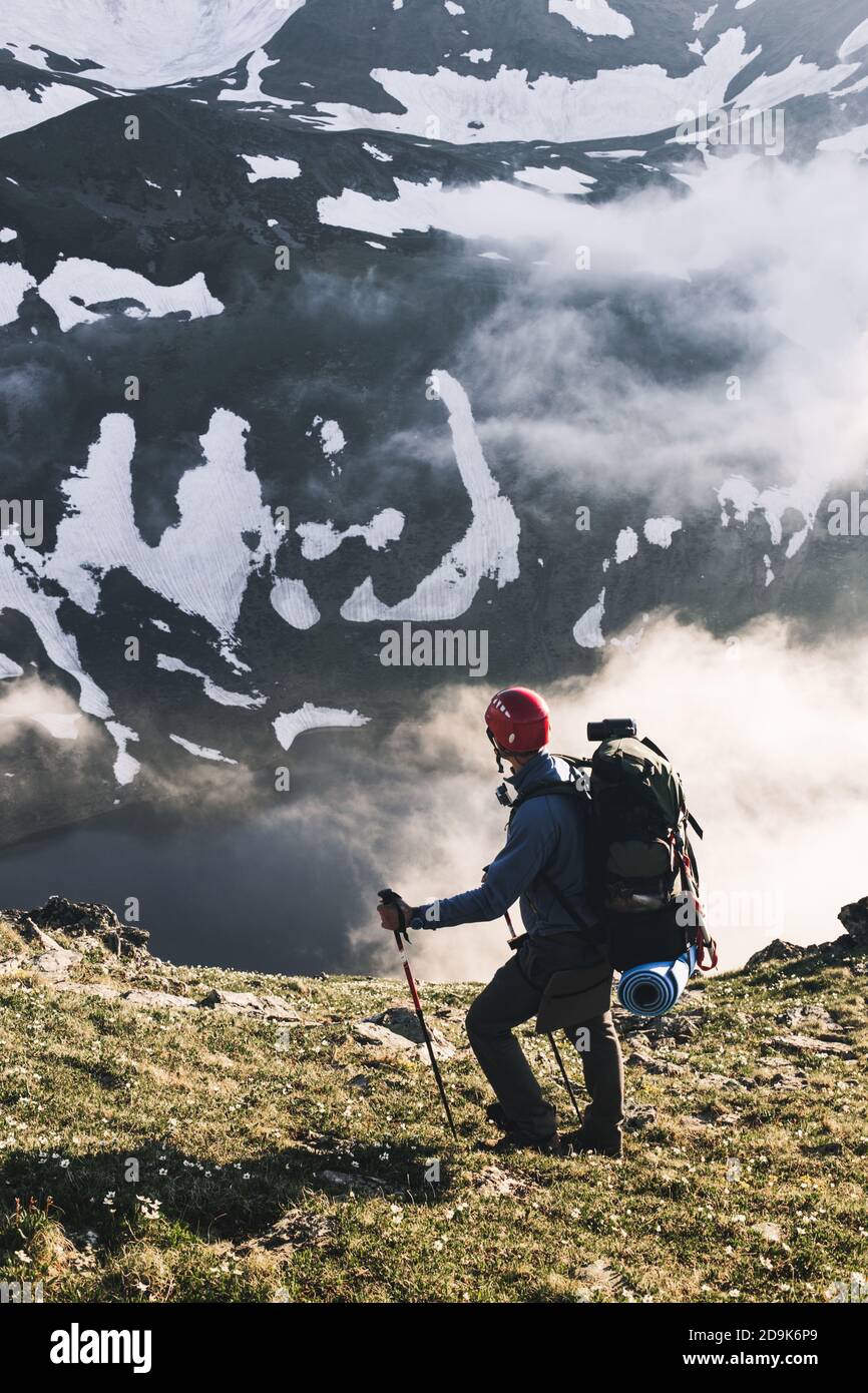 Traveler man hiking alone in mountains adventure active lifestyle traveling summer vacations outdoor solitude harmony with nature hiker standing on cl Stock Photo