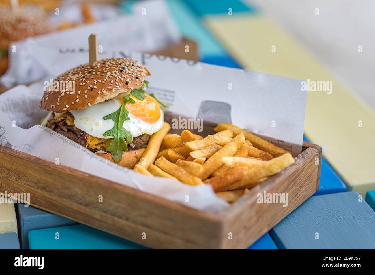 Hamburger and fries. Giant burger with french fries in wooden bowl plate. Gourmet homemade hamburger in outdoor restaurant table top Stock Photo