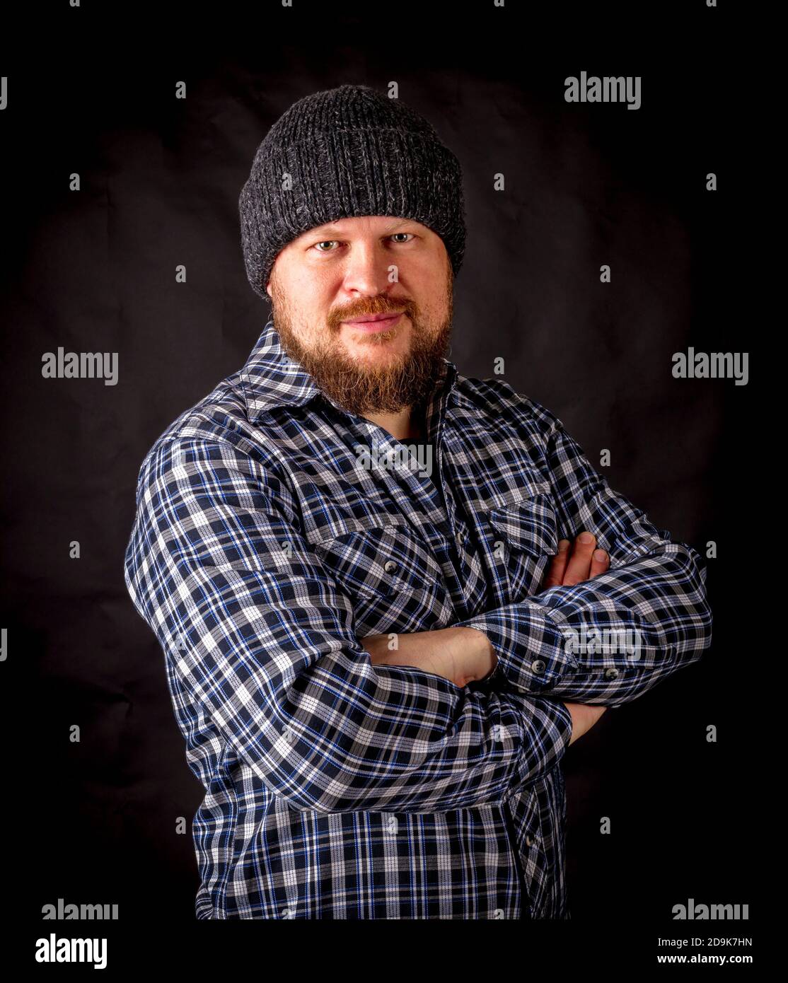 Solid bearded man in a wool cap portrait on black background Stock Photo