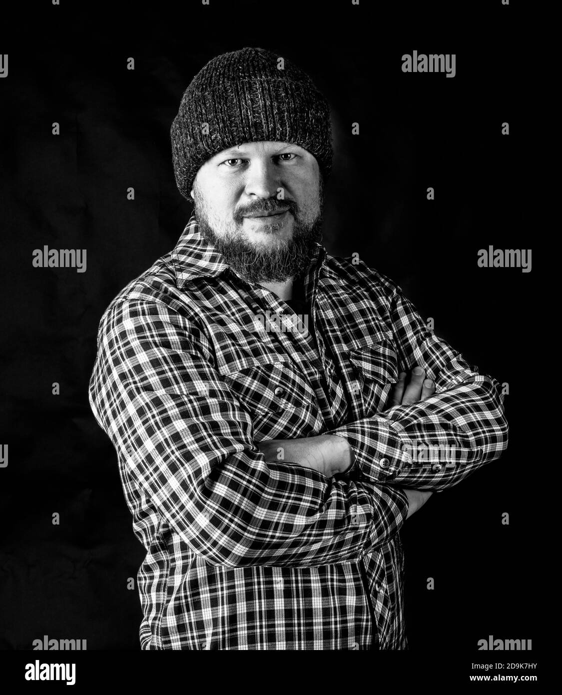 Solid bearded man in a wool cap portrait on black background Stock Photo