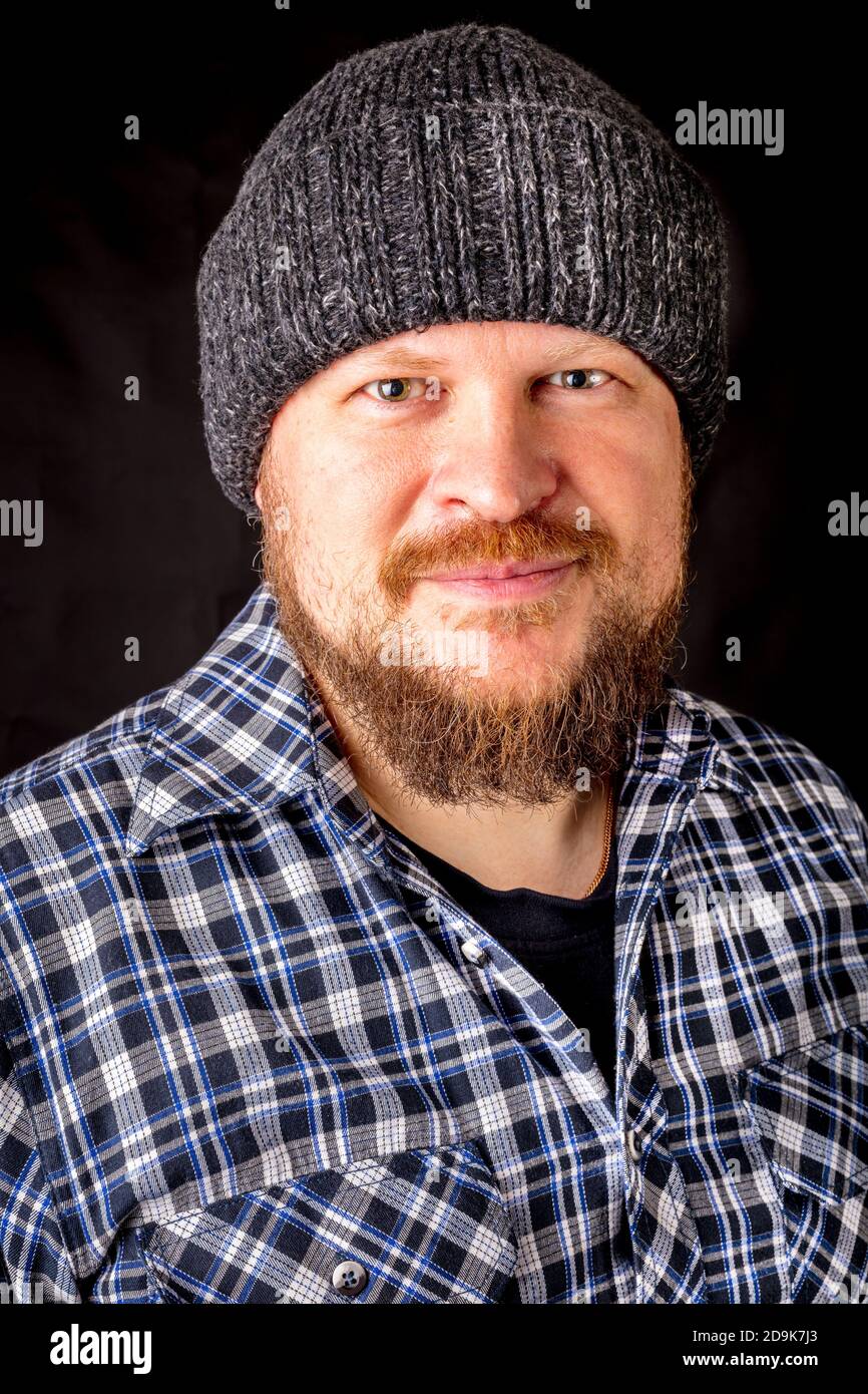 Solid bearded man in a wool cap portrait on black background Stock Photo